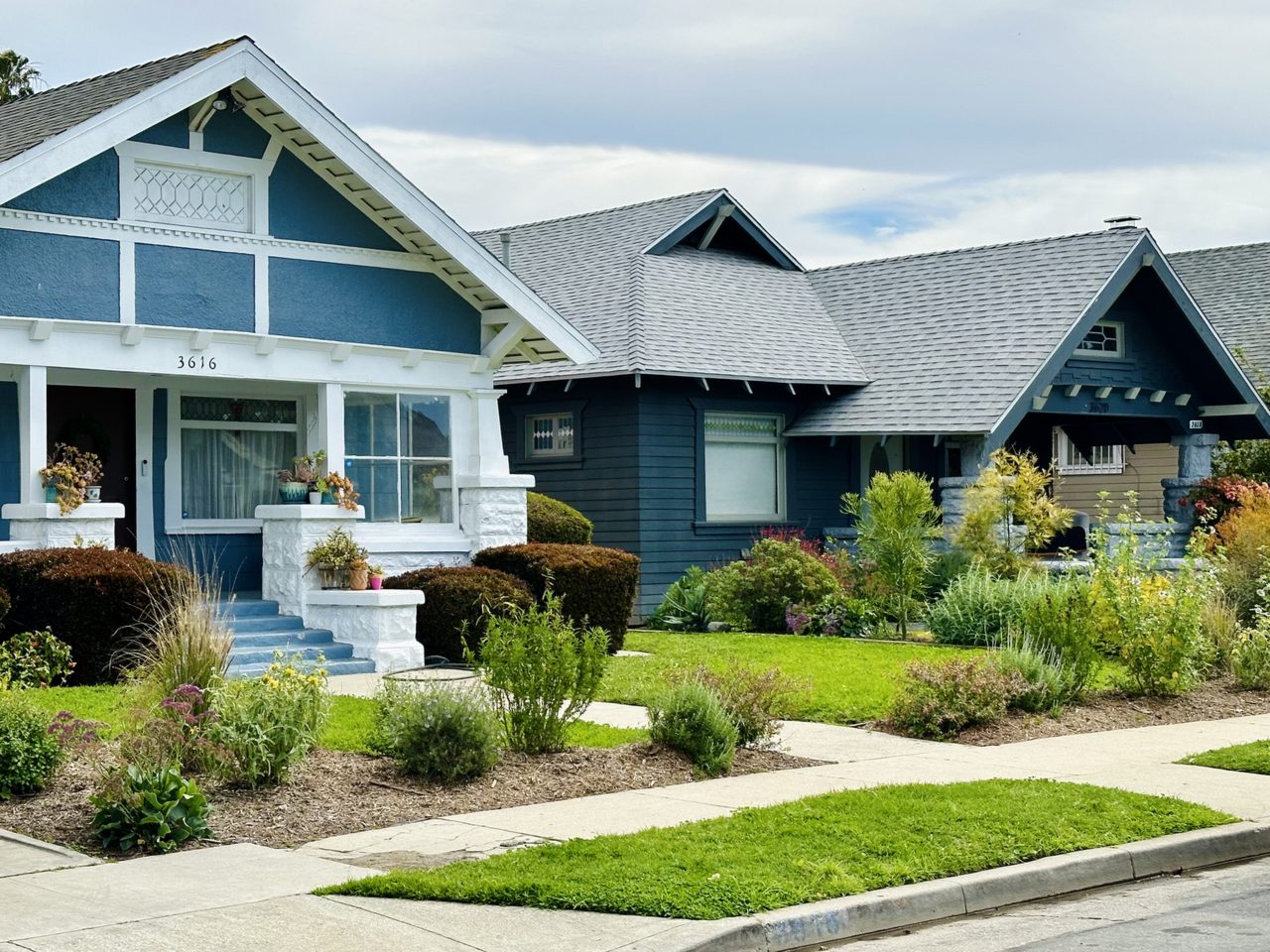 A row of early 1900s Craftsman bungalows with front lawns on a residential street in Jefferson Park, Los Angeles