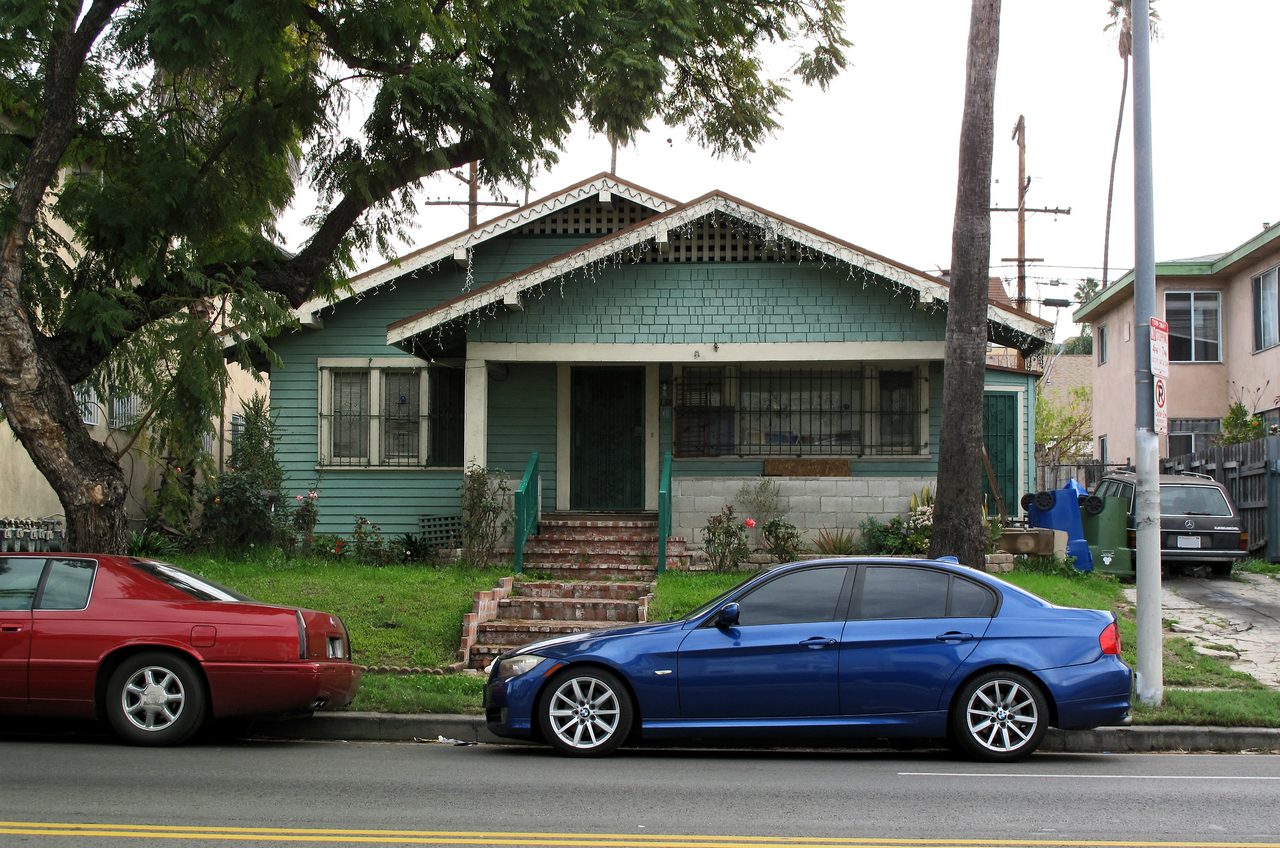 An older Craftsman bungalow with a front porch and brick steps on North Normandie Avenue in Los Angeles